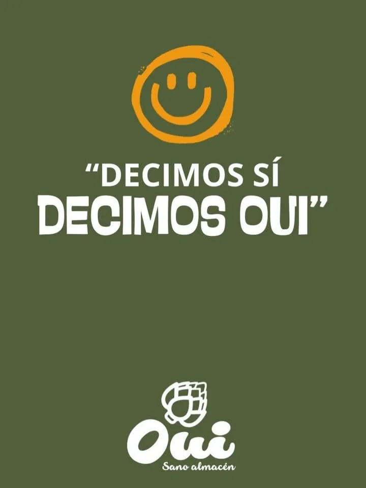 Placa de Oui: una carita sonriente naranja dibujada a mano sobre fondo verde oliva, con la frase Decimos sí, decimos Oui